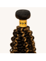 Détail de la bande tissée du tissage Kinky Curly P4/27 en cheveux naturels, avec finition soignée et mèches châtain blond doré.