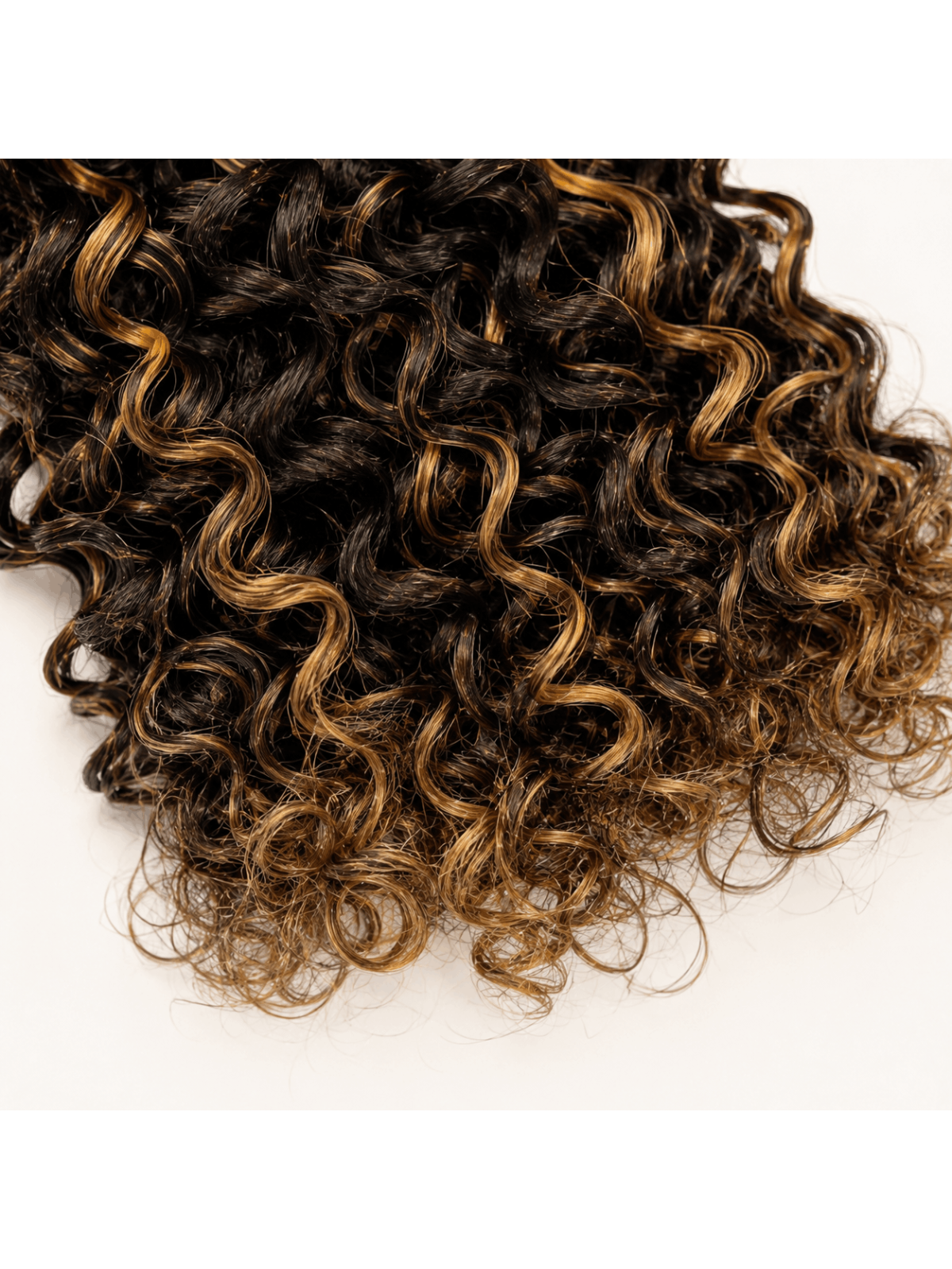 Gros plan sur la texture Kinky Curly P4/27 en cheveux naturels, mélange châtain N°4 et mèches blond doré N°27.